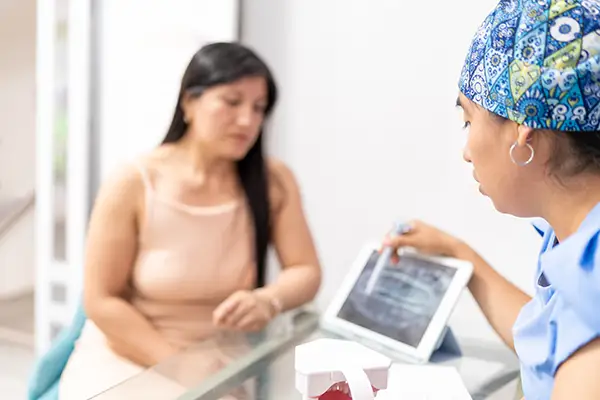 Dentist explaining oral cancer screening results on a tablet to a female patient, emphasizing early detection and prevention.